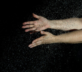 two female hands and flying drops of water on a black background