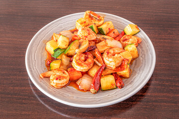 Chinese shrimp dish with vegetables, onions, zucchini with cayenne and hot sauce on a dark wooden...