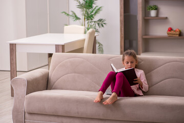 Small girl reading book at home