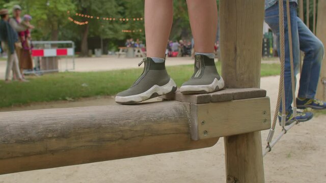 A teenager's feet tread on a wooden log in a forest school. He trains the vestibular apparatus. Active lifestyle of a child on vacation. The sole is non-slip.