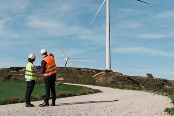 Engineer people using tablet at alternative energy wind green farm station wearing safety masks -...