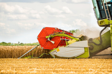 Combine harvester in action on wheat field. Harvesting is the process of gathering a ripe crop from...