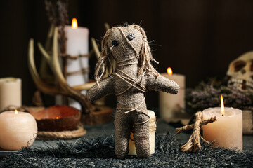 Voodoo doll pierced with pins and candles on table. Curse ceremony