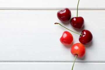 Obraz na płótnie Canvas Sweet red cherries on white wooden table, flat lay. Space for text