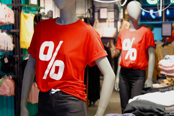 Two dummies in store shop mall in red t-shirts with percent symbol sign. Sales discounts concept.