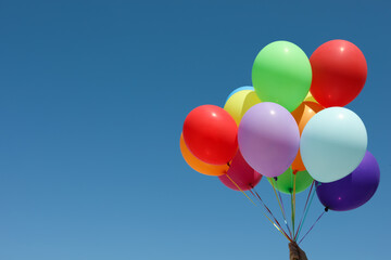Woman with bunch of colorful balloons against blue sky. Space for text