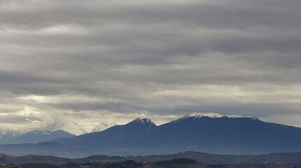 Obraz na płótnie Canvas Nuvole grigie sopra le montagne innevate e le valli degli Appennini
