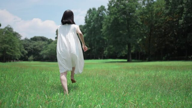 緑に囲まれた草原を走る女の子