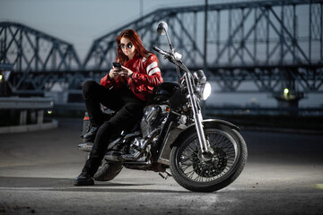 Fototapeta na wymiar Girl biker sexually posing on motorcycle at night city