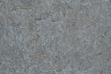 The texture of the gray surface of the stone with inclusions of marble and yellow veins.