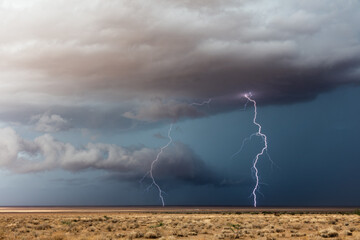 Lightning bolts strike ahead of a storm with dark clouds