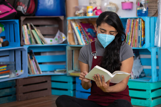 Mexican Young Teacher Reading A Book On An Empty Classroom