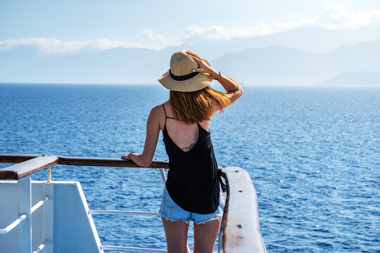 Elegant woman with casual dress and hat on a ferry boat on the Aegean sea, Cyclades, Greece
