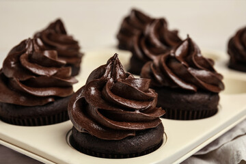 Delicious chocolate cupcakes with cream in baking tray, closeup