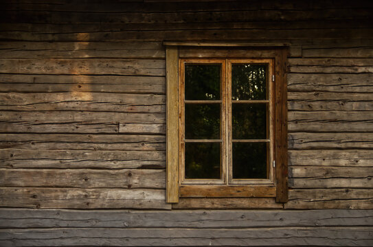 Old wooden log house window frame exterior with glass