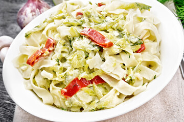 Fettuccine with zucchini and hot peppers in plate on dark wooden board