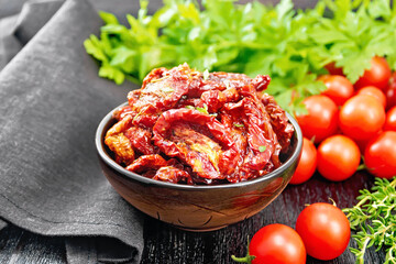 Tomatoes sun-dried in bowl with napkin on board
