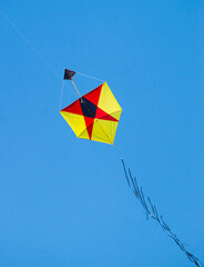 pipa brasileira amarela e vermelha com desenho geométrico voando em ceu azul