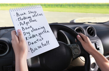 Woman with to do list in driver's seat of car, closeup. Stress overload concept