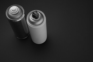 Cans of different graffiti spray paints on black background, above view. Space for text