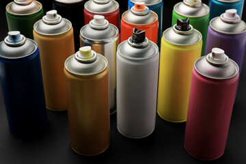 Cans of different graffiti spray paints on black background