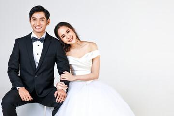 Young attractive Asian couple, soon to be bride and groom, woman wearing white wedding gown. Man...