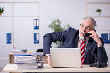 Old male employee sitting at workplace