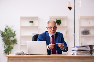 Old male employee in blood transfusion concept