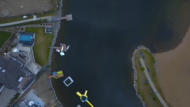 aerial birds view twist over recreational backyard homes with kayaks paddle boats canoes docked on a hot summer day next to clear sandy beaches blue clean manmade pond nobody outside Summerside AB 3-3