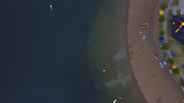 aerial flyover Summerside manmade pond in the southside of Edmonton Alberta's beach clubhouse where locals enjoy the sunny summer day birds view surrounded by a playground and a dock for boaters 2-4