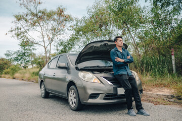 Serious man fold one’s arms over the chest front of car breakdown and open bonnet on roadside. Car broken concept.