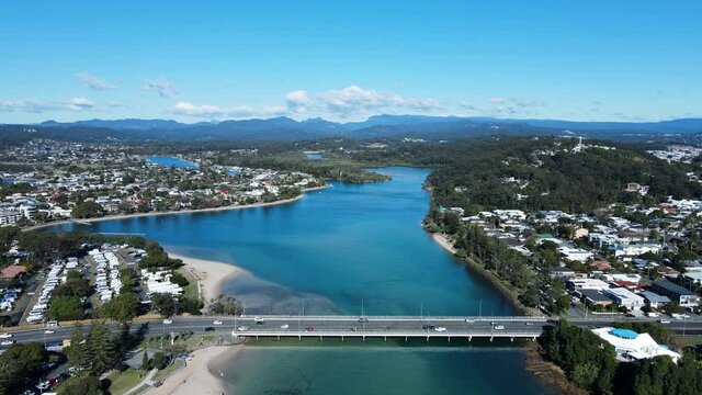 High scenic panorama of Tallebudgera Creek bridge with the Gold Coast hinterland in the foreground. Moving drone view