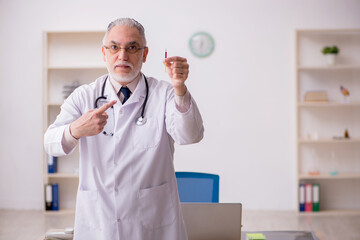 Old male doctor in vaccination concept