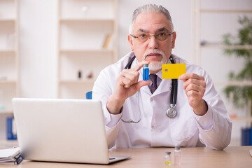 Old male doctor in credit card payment and vaccination concept