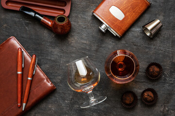 Glass of brandy or cognac  and accessories on  dark table, top view