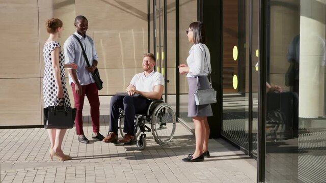 Portrait of disabled businessman and colleagues talking and leaving office together