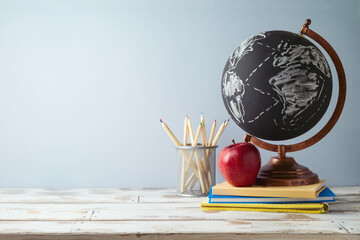 Back to school concept with pencils, apple and globe on wooden table.