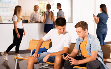 School Boys using phones, have rest between lessons at hallway in school