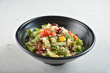 couscous healthy grain salad bowl with corn, bean, carrot and salad dressing sauce in white marble healthy poke bowl menu