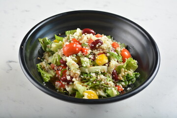 couscous healthy grain salad bowl with corn, bean, carrot and salad dressing sauce in white marble healthy poke bowl menu