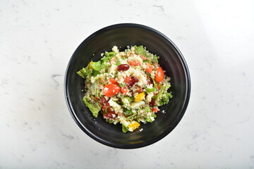 couscous healthy grain salad bowl with corn, bean, carrot and salad dressing sauce in white marble healthy poke bowl menu
