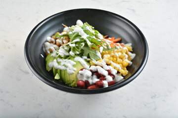 colourful healthy bowl assorted salad, vegetables, avocado, corn, bean, carrot and salad dressing sauce in white marble healthy poke bowl menu