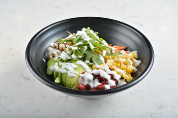 colourful healthy bowl assorted salad, vegetables, avocado, corn, bean, carrot and salad dressing sauce in white marble healthy poke bowl menu
