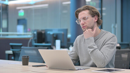 Fototapeta premium Young Man with Laptop Taking Nap in Office