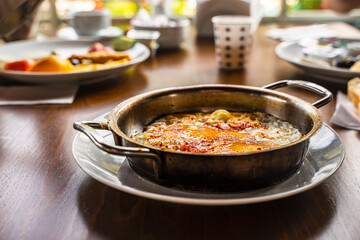 Delicious scrambled eggs served in a frying pan on a wooden background with space for text.