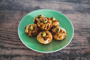 vegan focaccia savory muffins with sundried tomatoes and olives served on a green plate, healthy plant-based food