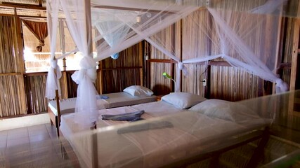 Looking into a tradition beach hut with a four poster bed on a tropical island in Timor Leste, South East Asia - Powered by Adobe
