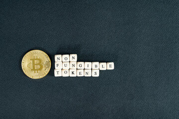 Digital currency concept. Non fungible tokens text on plastic blocks with bitcoin