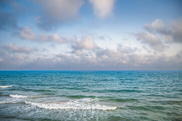 Beautiful beach in sunny summer day. Turquoise ocean water and blue sky with clouds . Natural background for summer vacation, soft focus, space for text