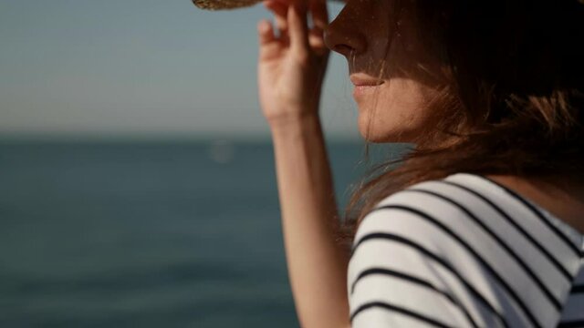 Close-up portrait of a woman in a big hat resting on a walk by the sea. Outdoor vacation in the open air. The concept of a healthy and happy lifestyle.